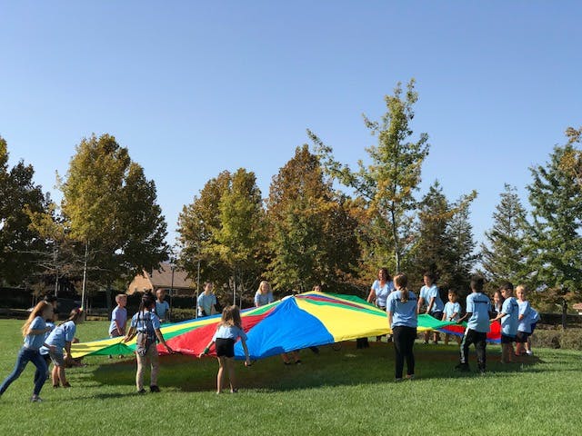 People playing with a colorful parachute on a grassy field