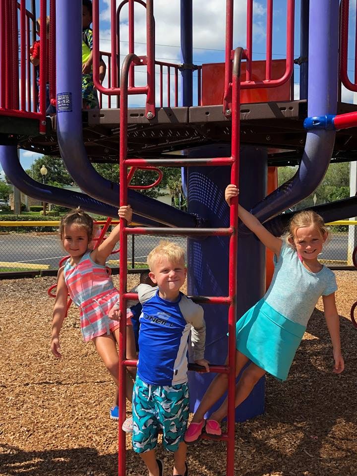 Three children on a playground climbing structure