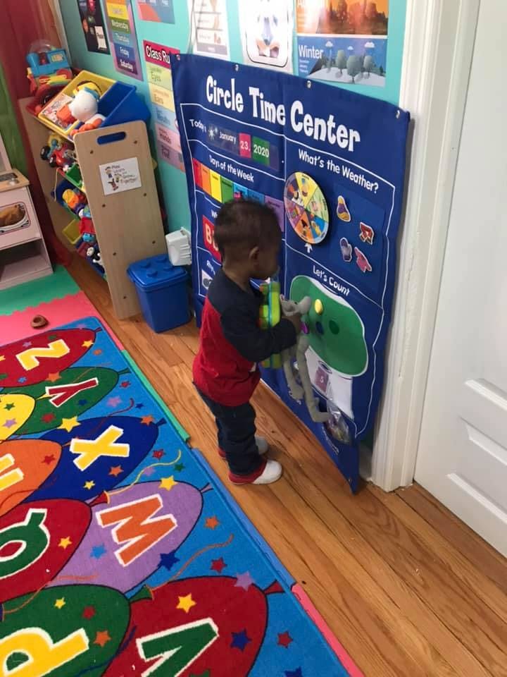 Child interacting with a blue "Circle Time Center" activity board