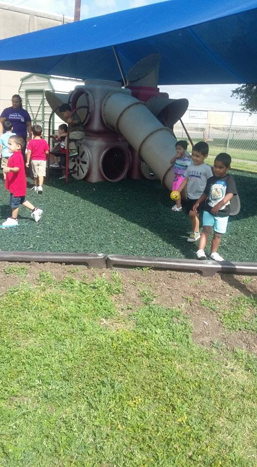 Children playing on a playground with a slide and climbing structure