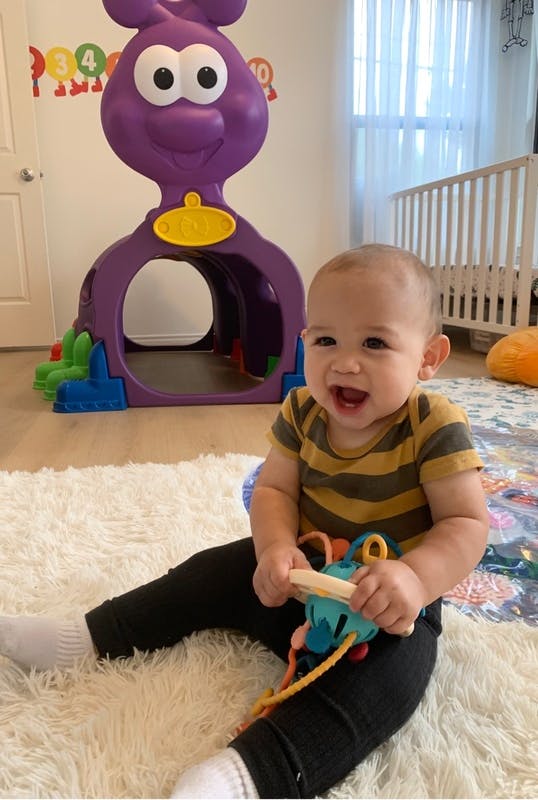Child sitting on a rug holding a toy