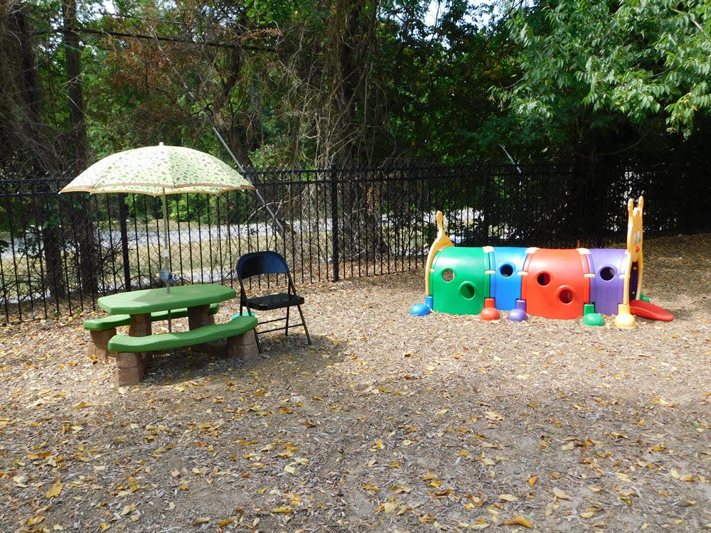 Outdoor play area with a picnic table, umbrella, and colorful play tunnel