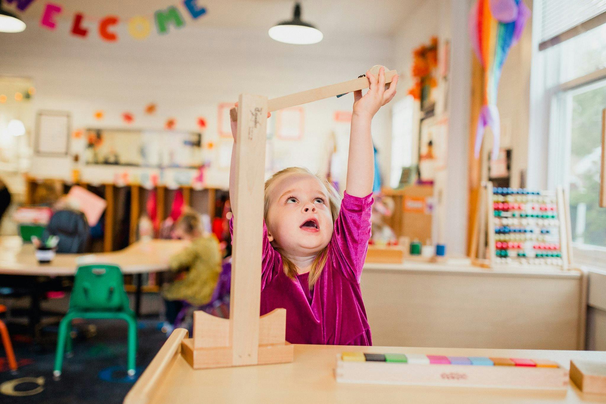 Child playing with a wooden toy in a classroom