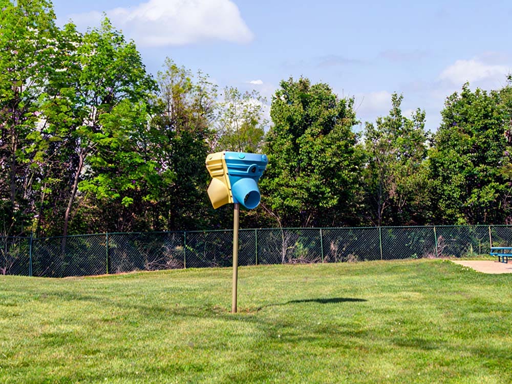 Pet waste station in a grassy area with trees in the background