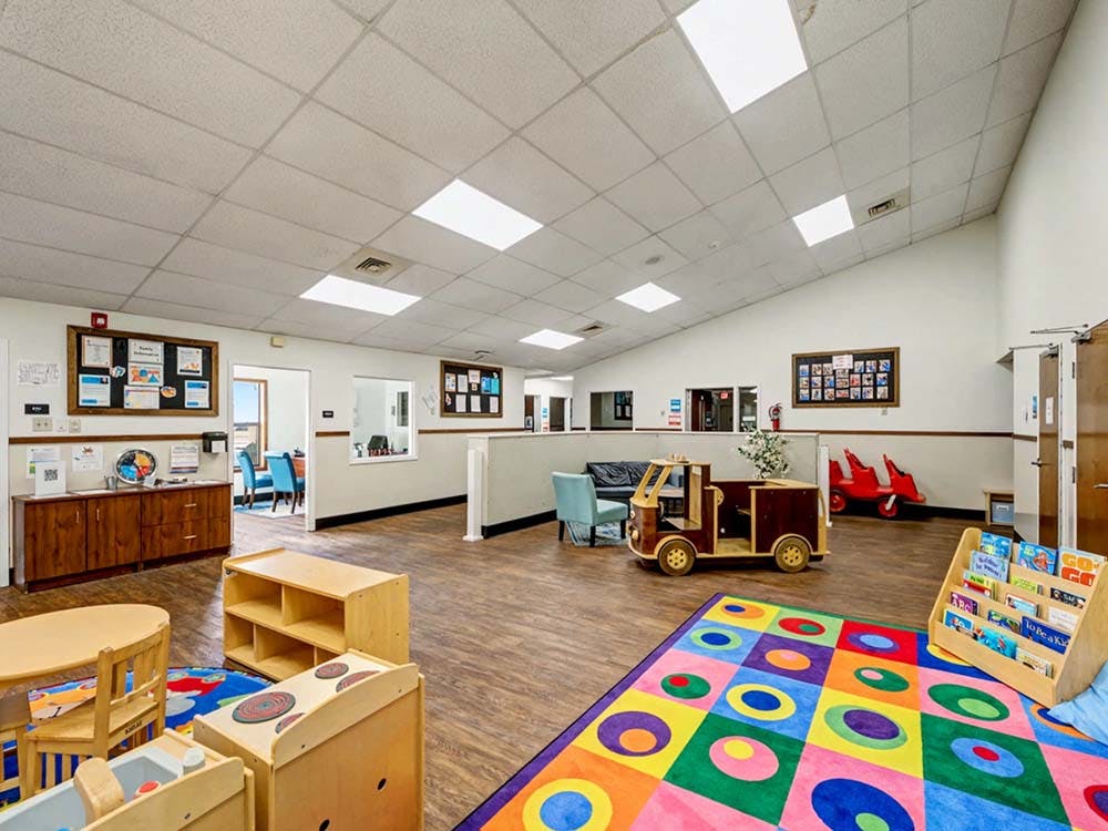Children's play area with a colorful rug, toys, and small furniture in a room