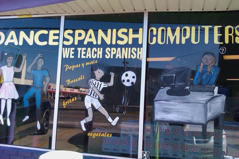 Storefront window with painted figures and text for dance, Spanish, and computers
