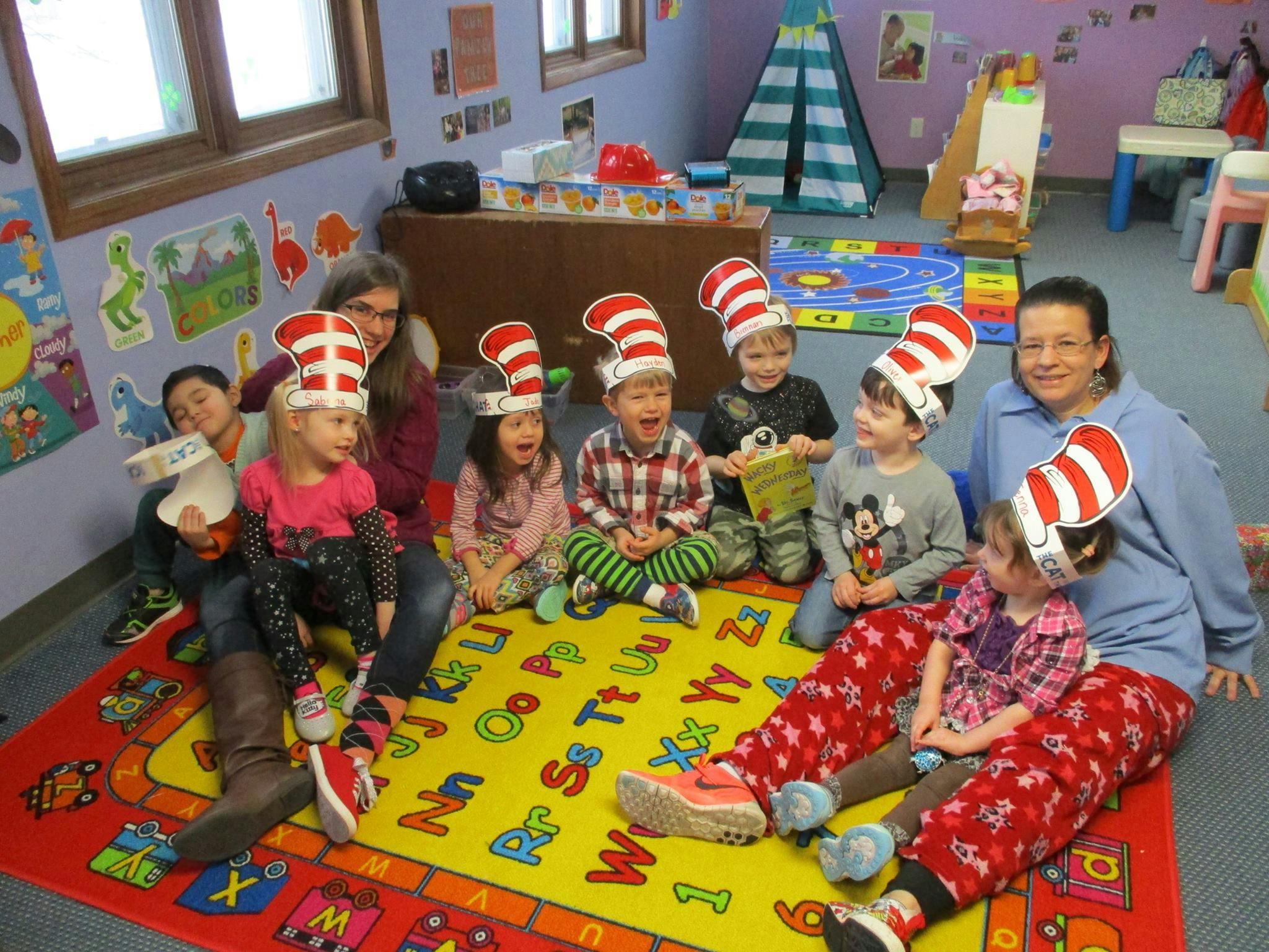 Adults and children wearing striped hats sitting on a rug