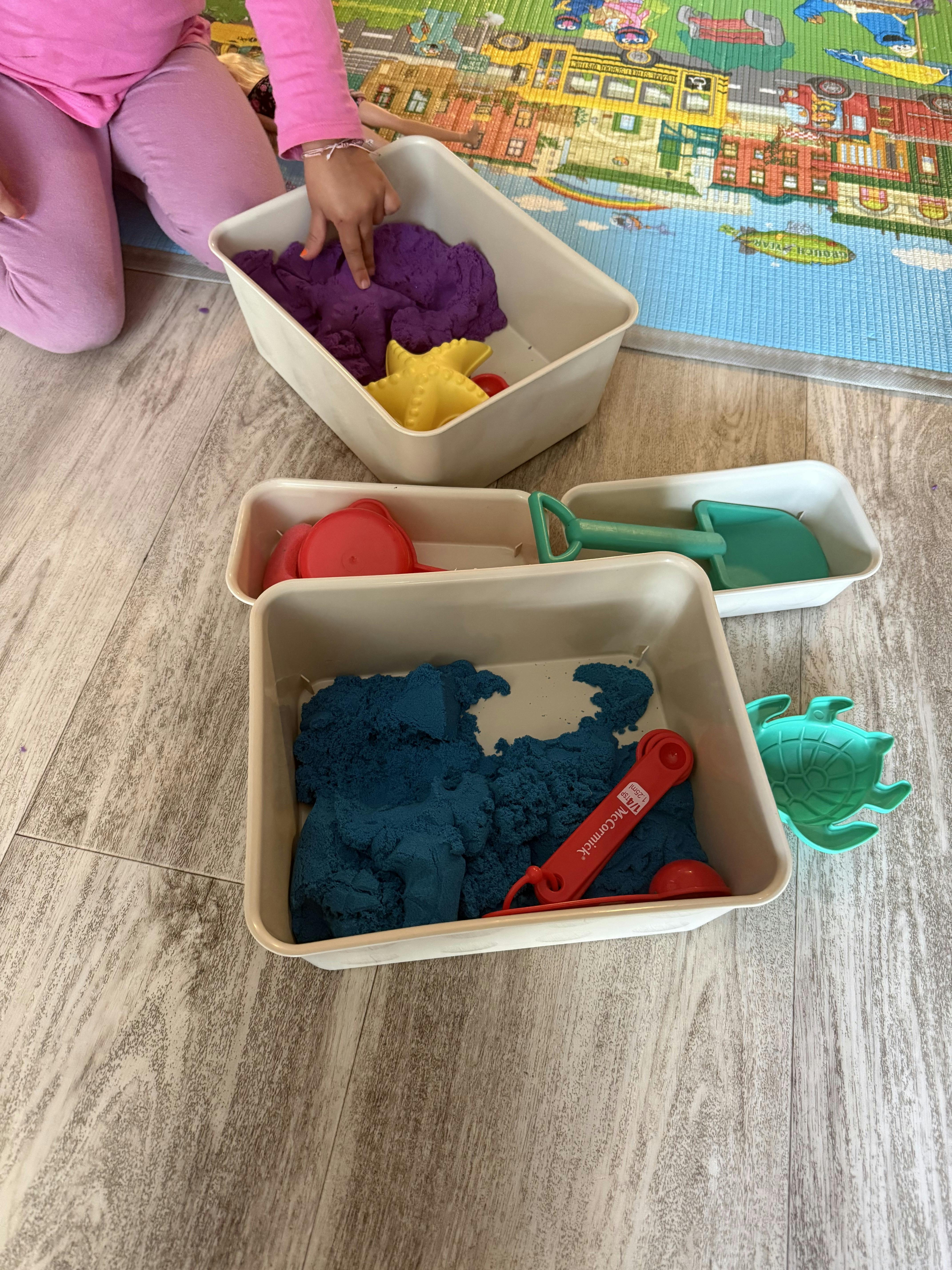 Child playing with purple and blue kinetic sand and plastic toy molds