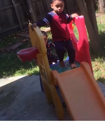 Child standing on top of a small slide