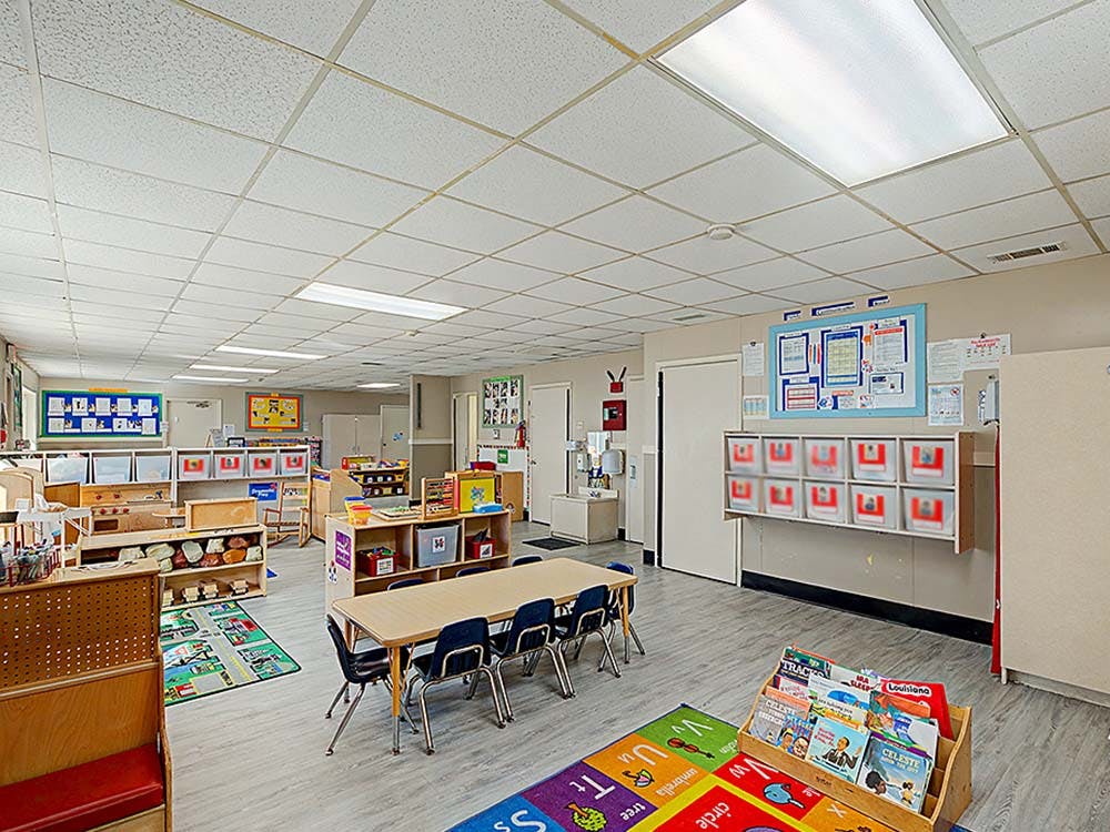 Empty classroom with several tables and shelves with toys