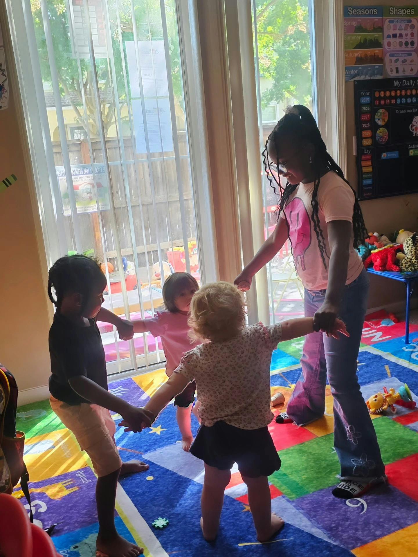 Four children holding hands in a circle on a colorful rug