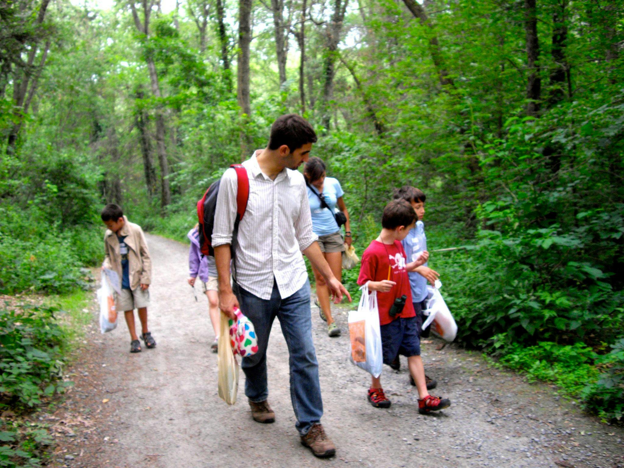 Adult and children walking on a path in a wooded area
