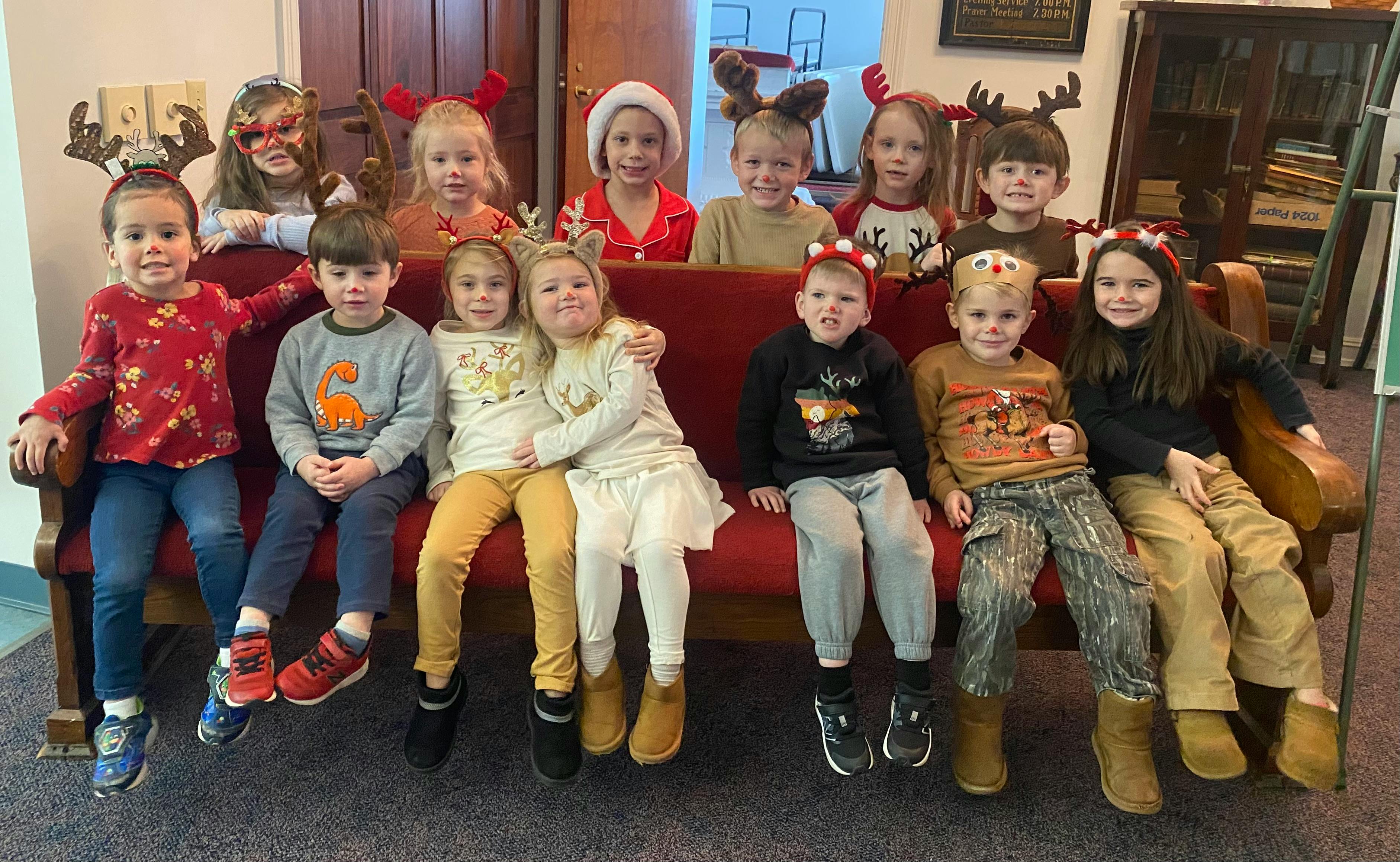 Group of children wearing holiday headbands sitting on a bench