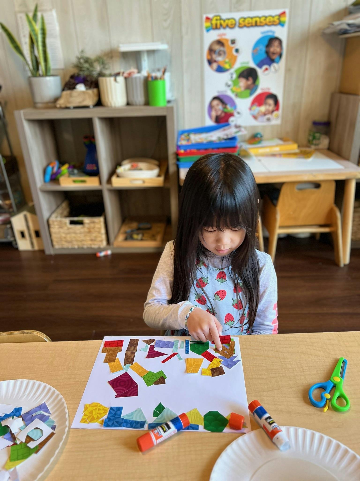 Child making a collage with paper scraps and glue sticks
