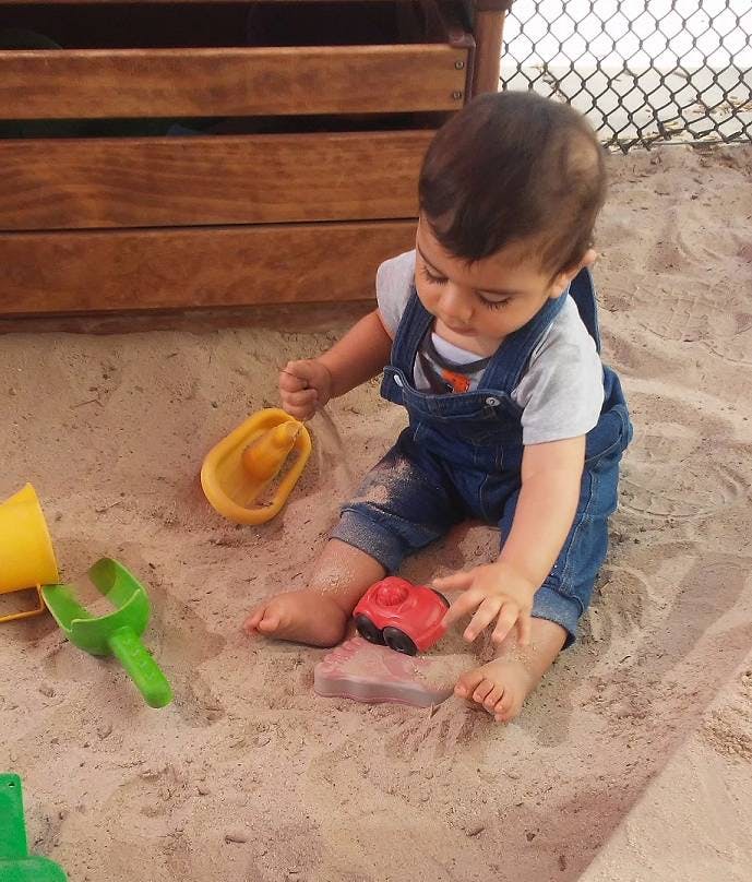 Child playing in sand with toys