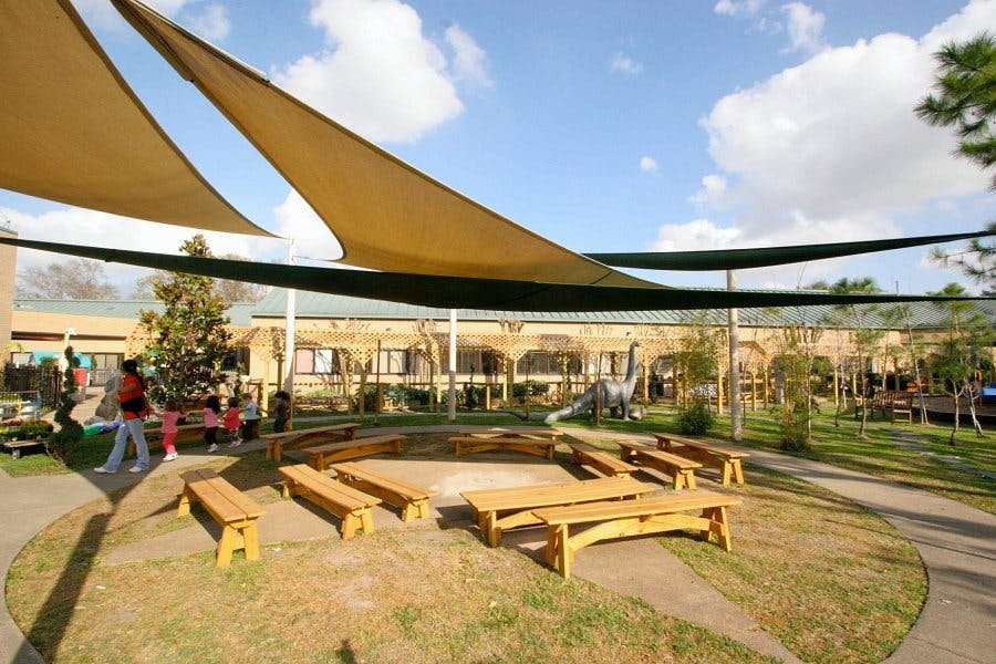 Outdoor classroom with wooden benches under shade sails