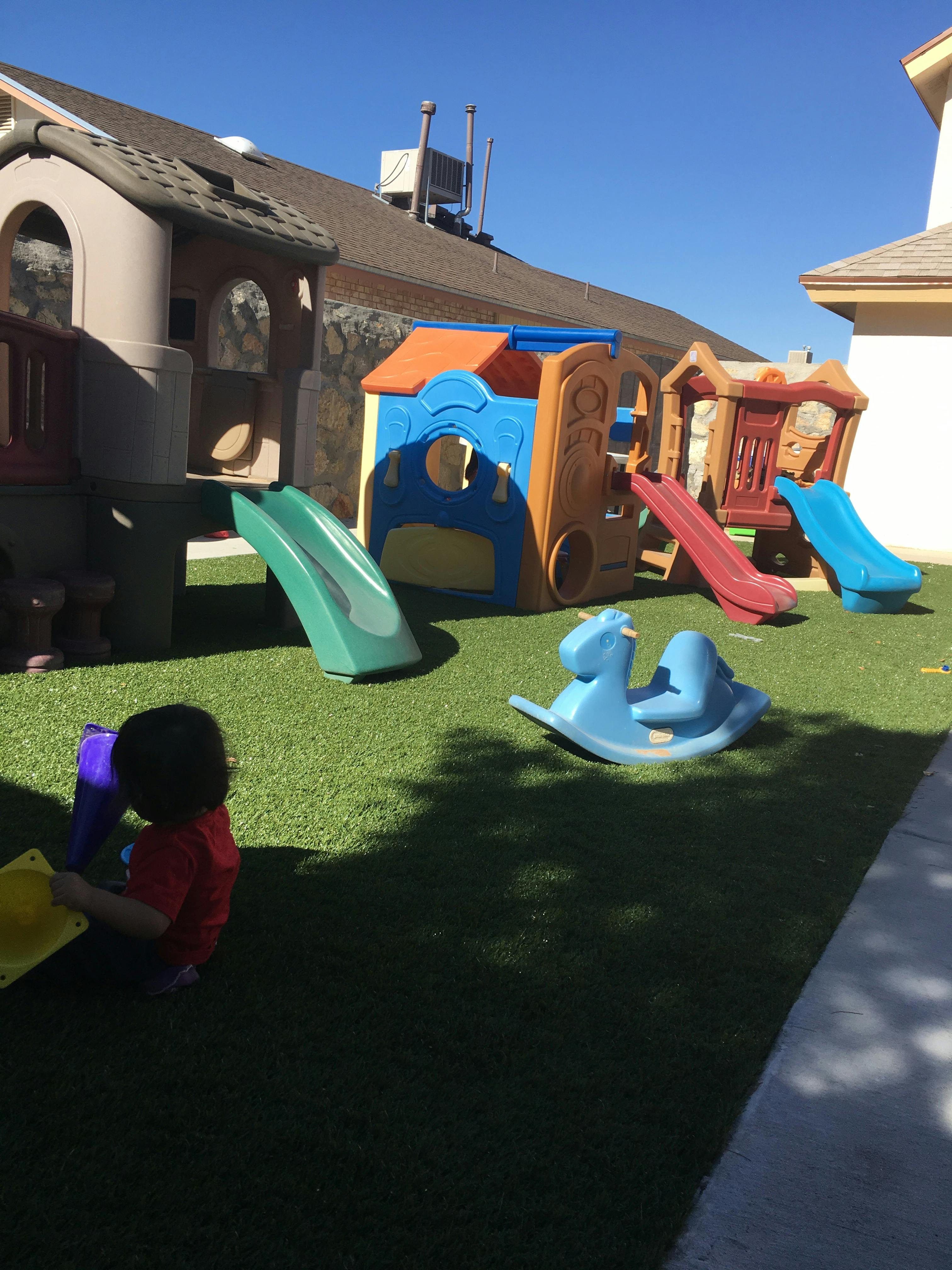 Child sitting on grass next to playground equipment