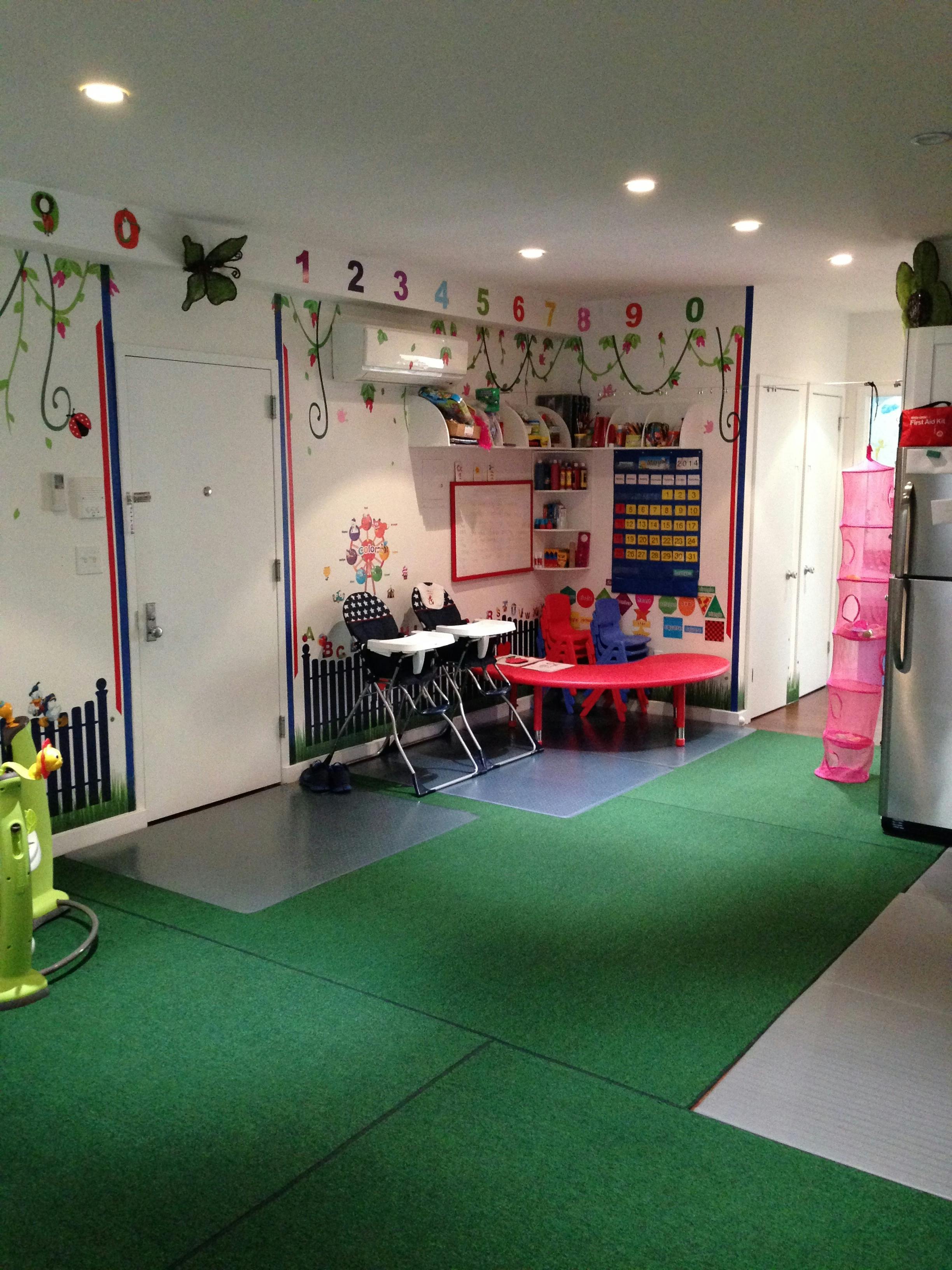 Playroom with green floor, small red table, and high chairs