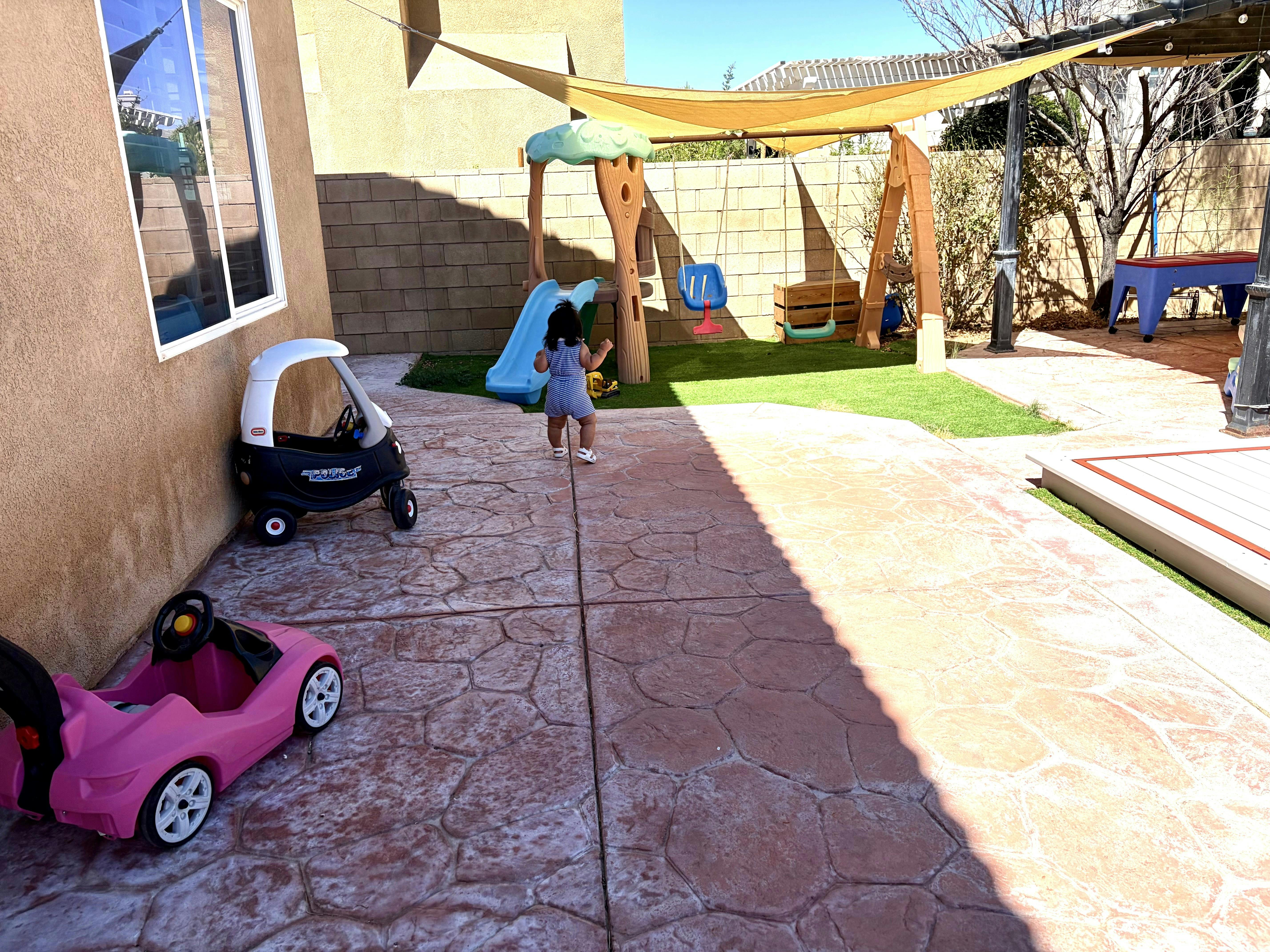 Child walking toward a playground set in a backyard