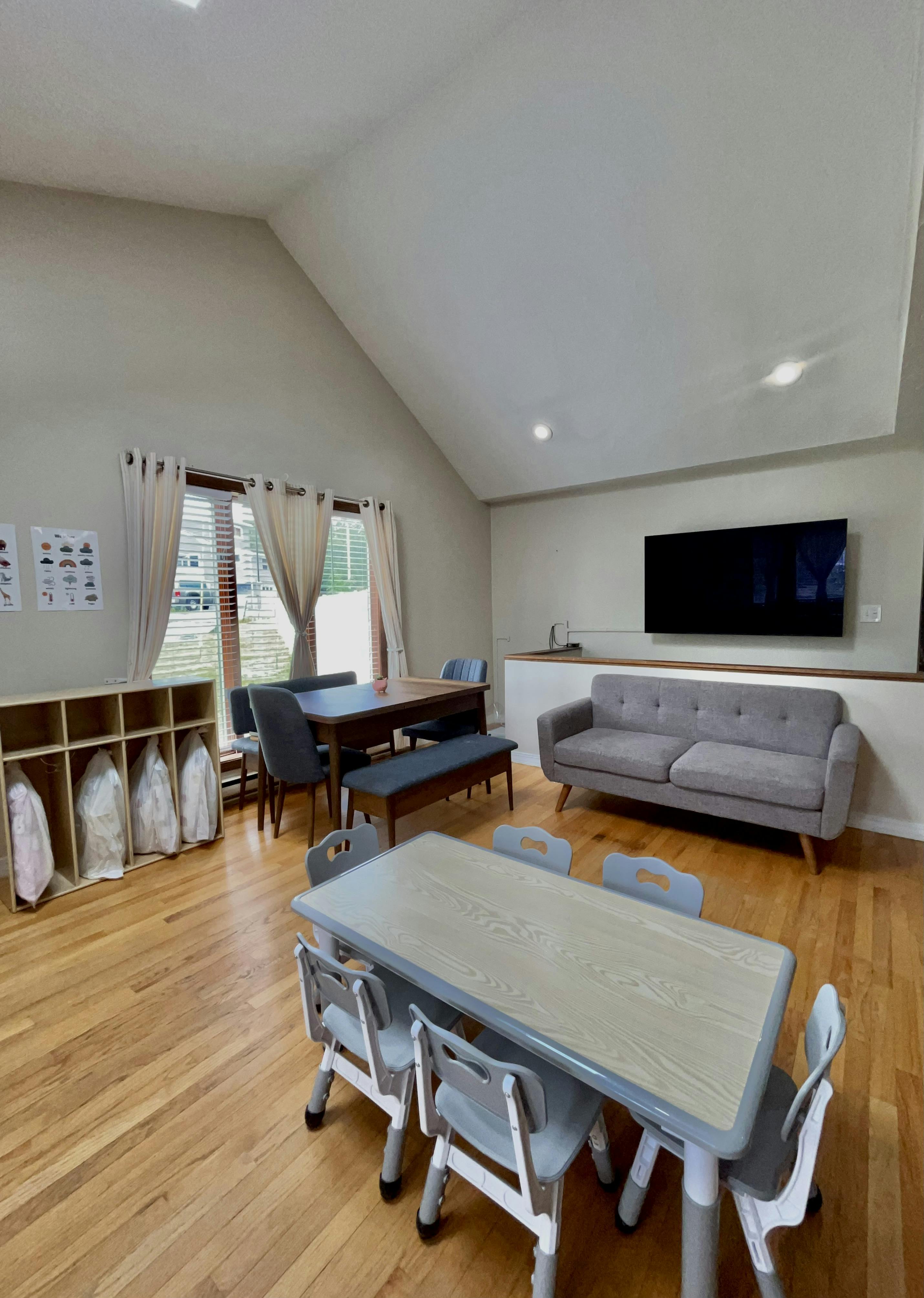 Room with a large TV, sofa, and multiple tables and chairs