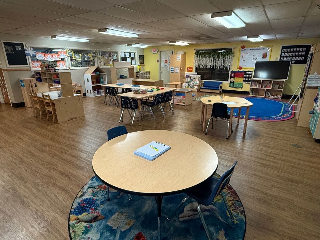 Classroom with tables, chairs, and shelves of learning materials