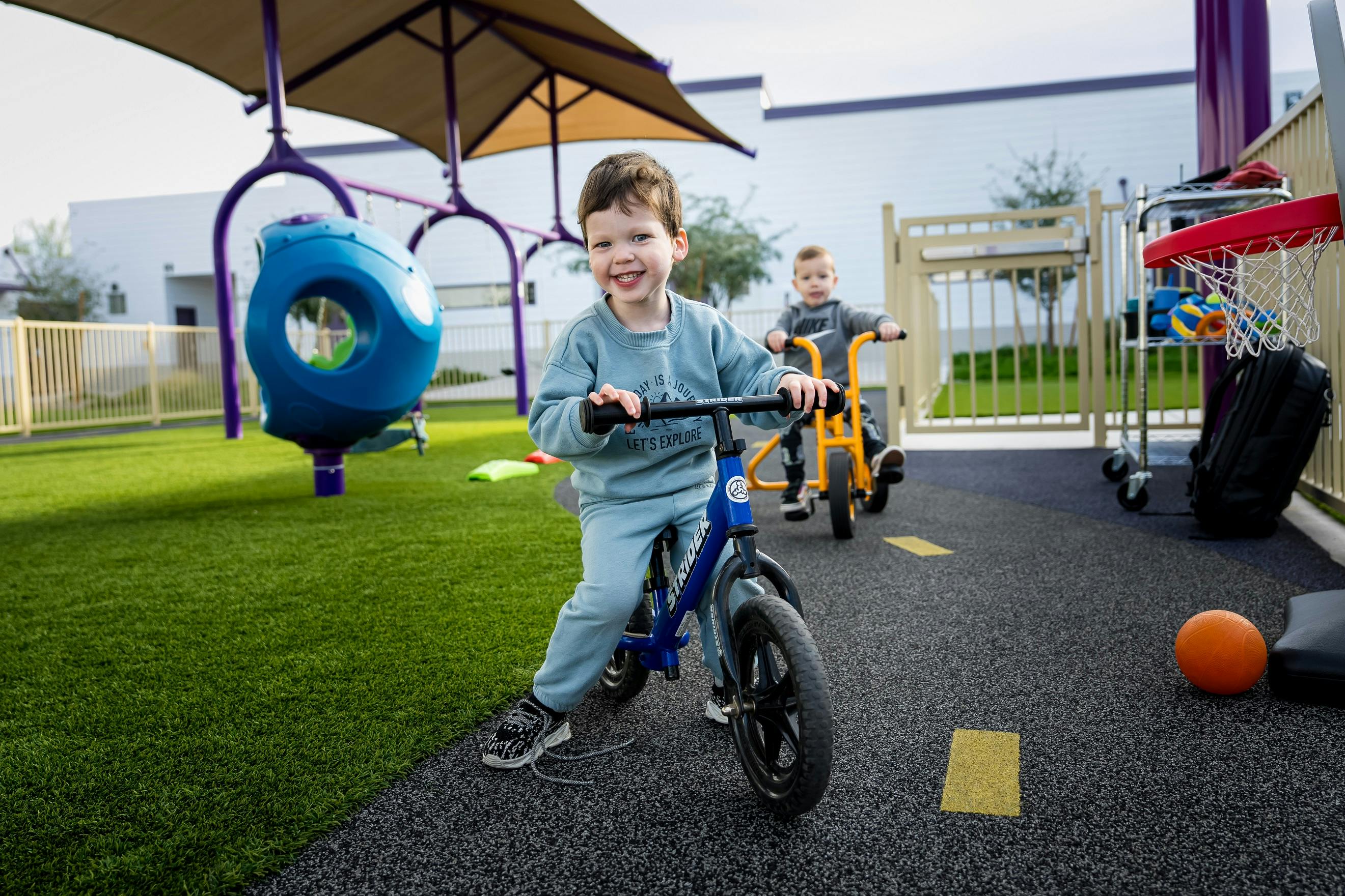 Two children riding balance bikes on a playground