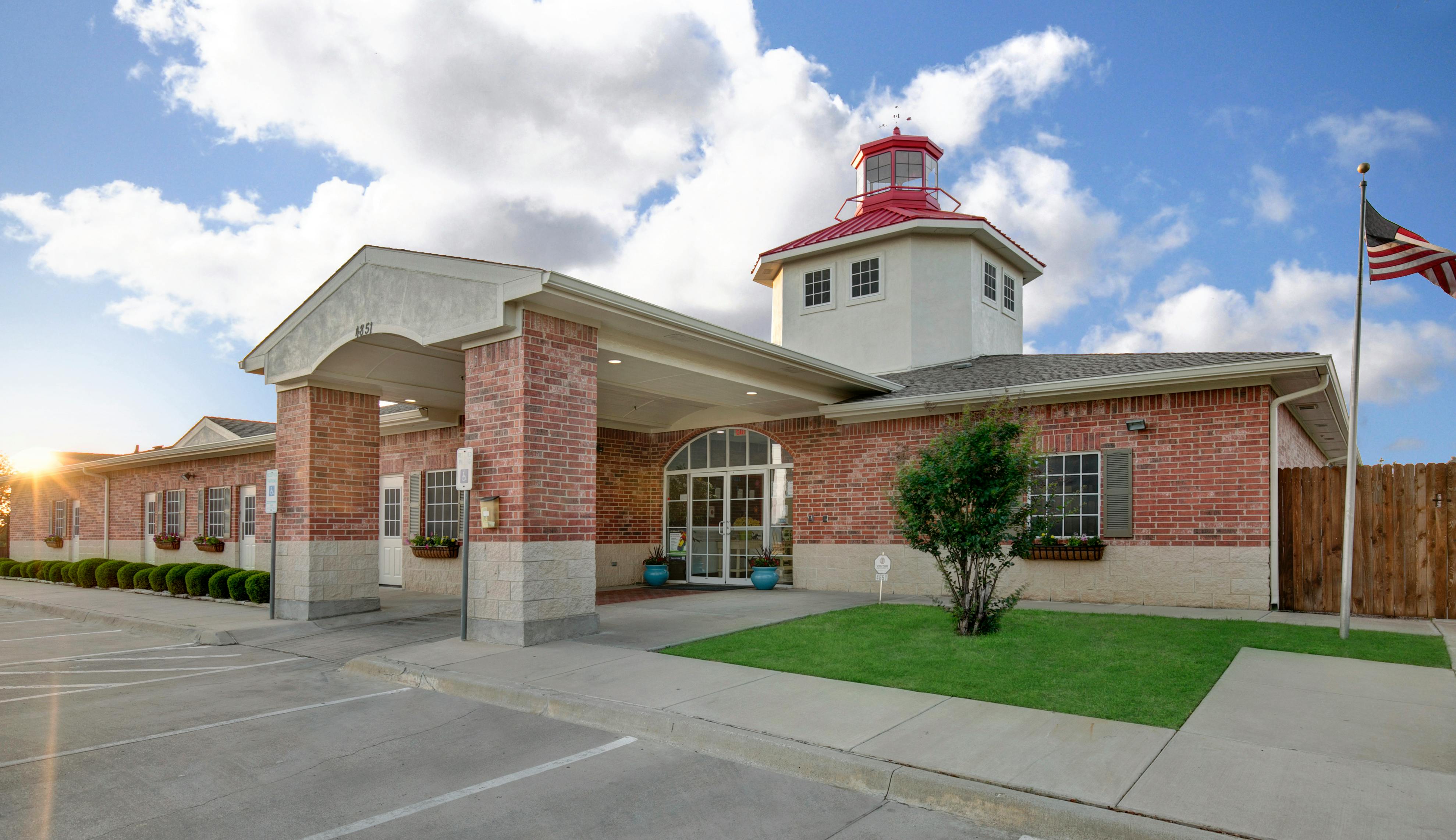 Brick building with a white tower and red roof, American flag flying