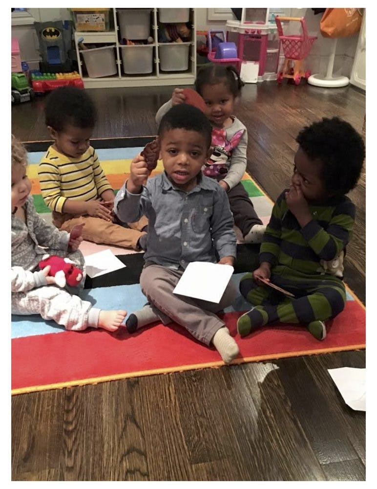 Children sitting on a colorful mat, one child holding a small object