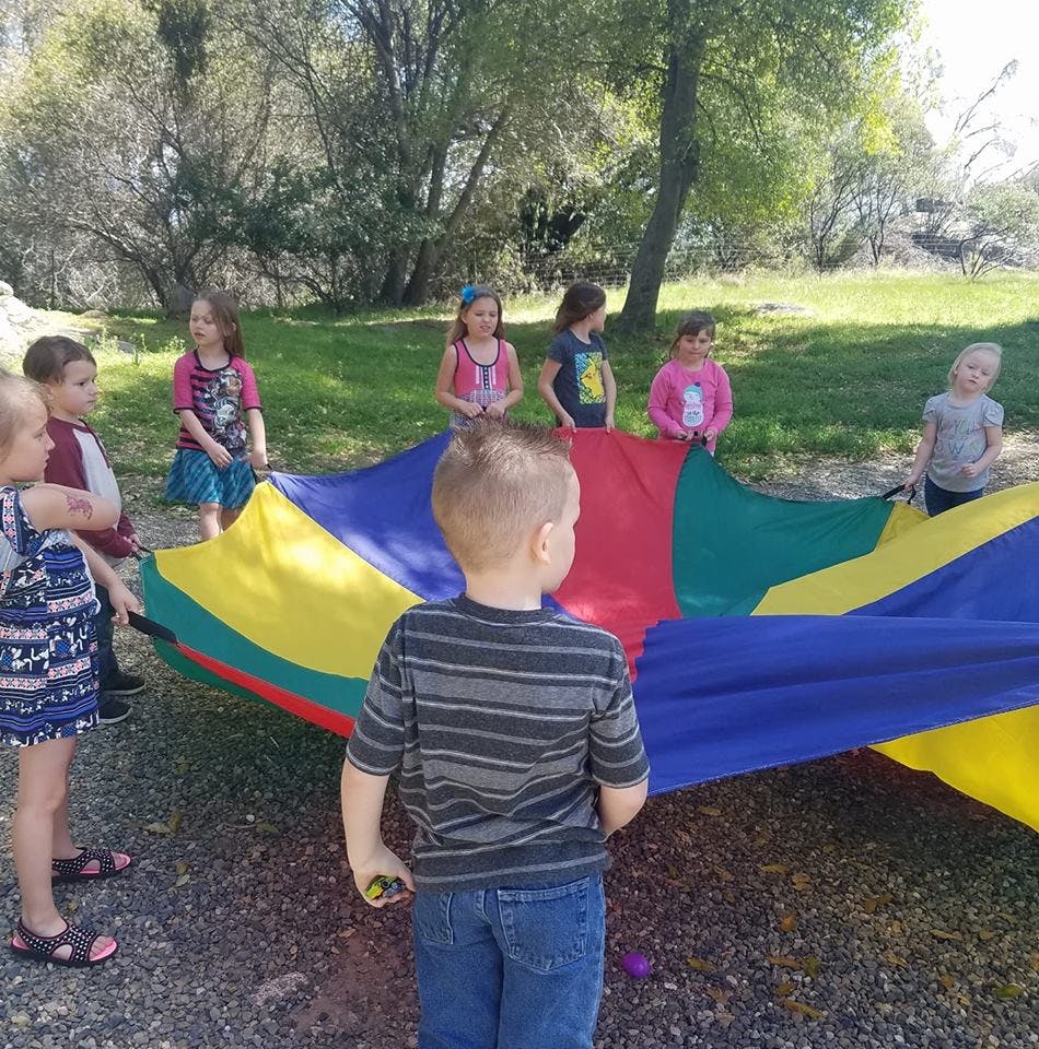 Children playing with a colorful parachute outdoors