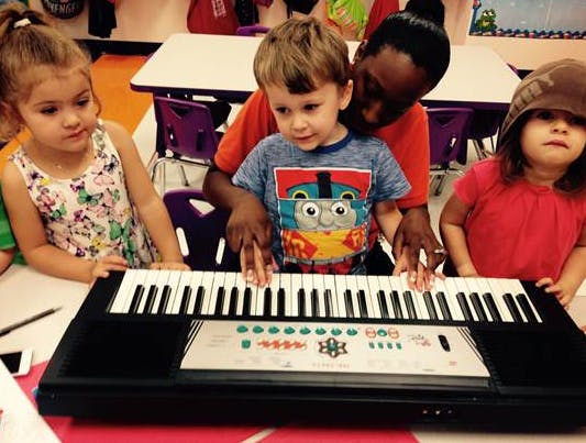Adult and three children playing a keyboard