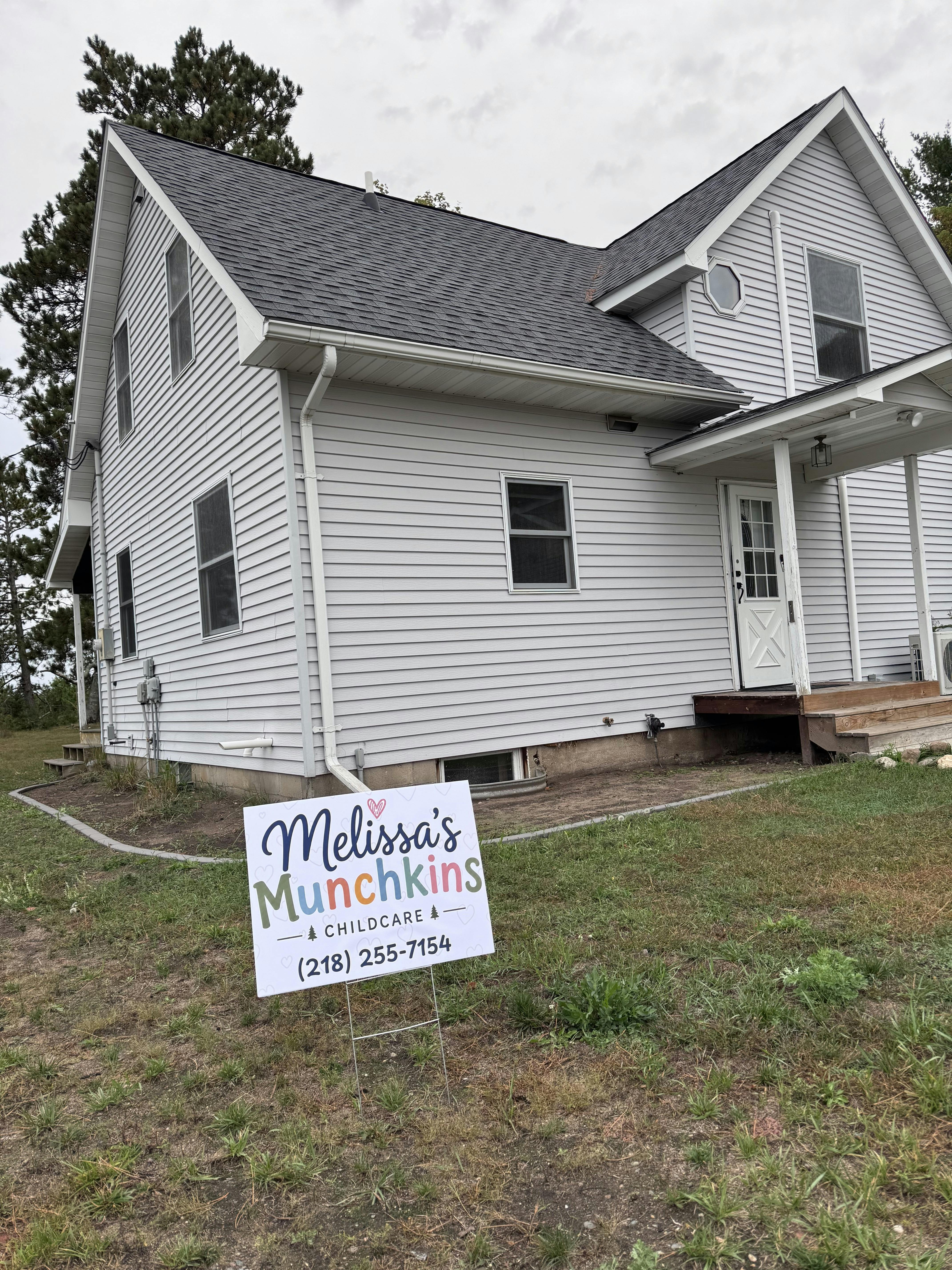 Sign for Melissa's Munchkins Childcare in front of a house