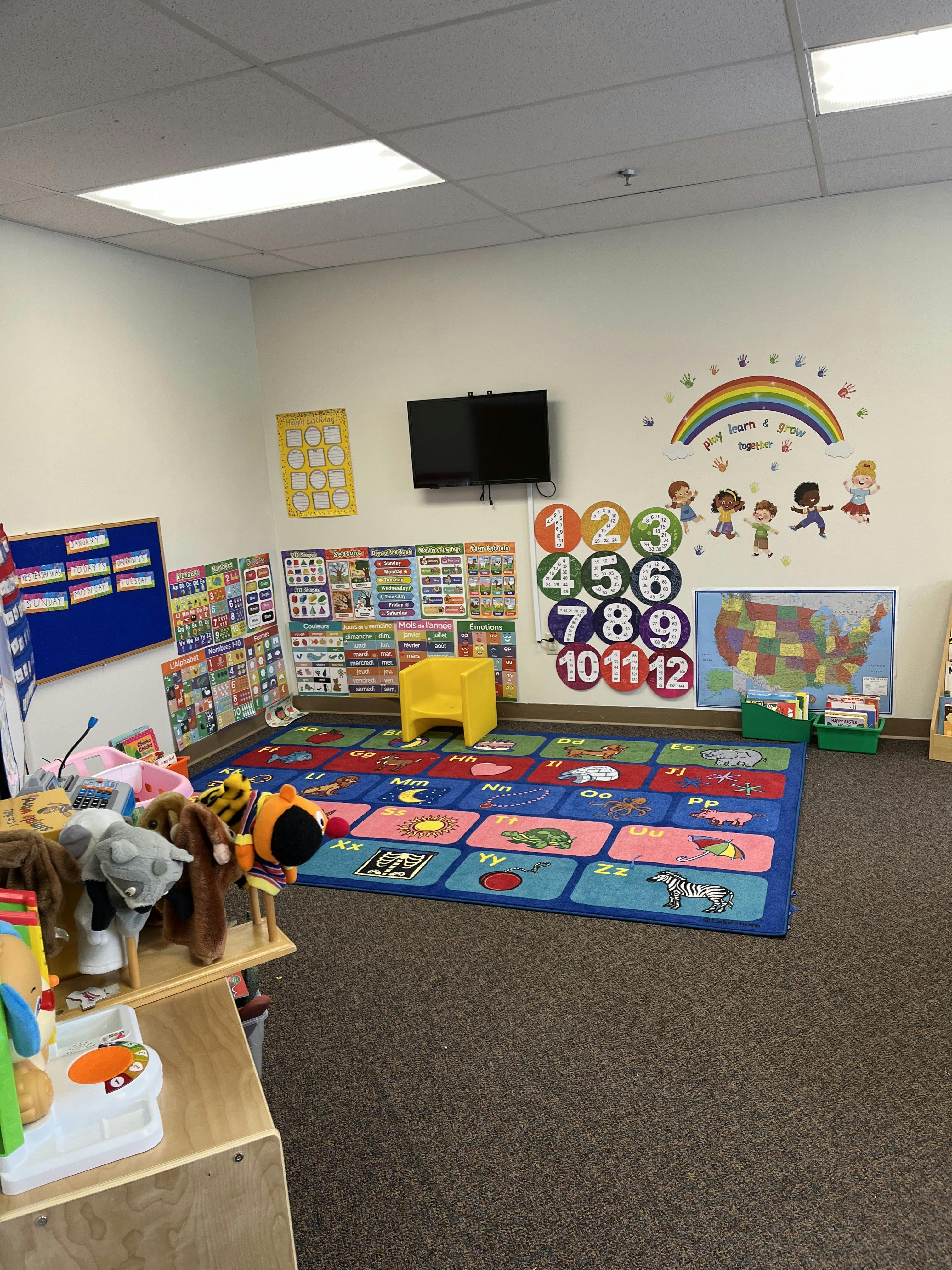 Classroom with an alphabet rug, learning posters, and children's toys