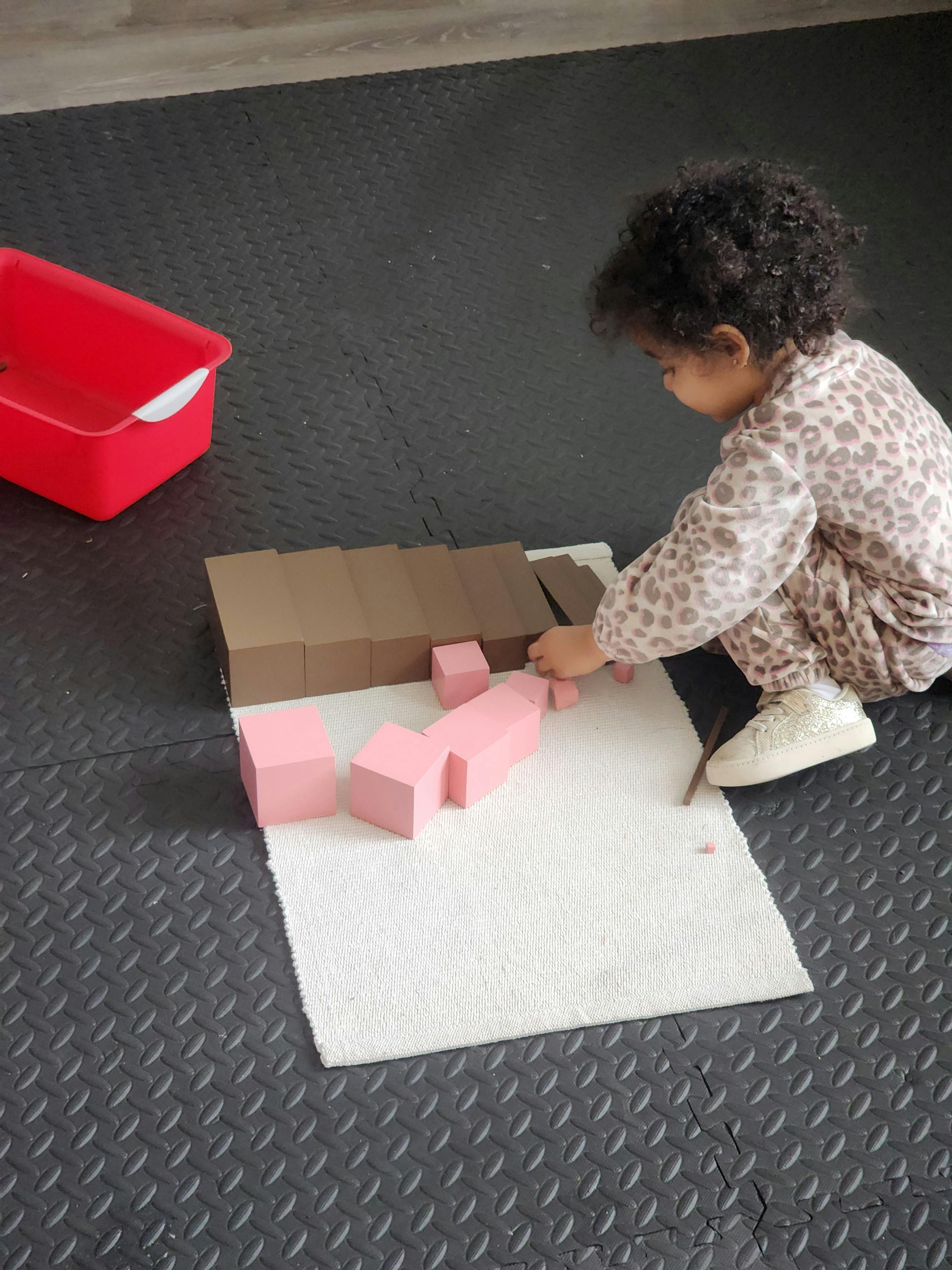 Child building with brown and pink blocks on a white mat