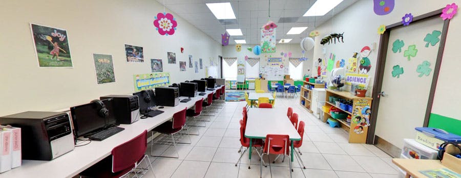 Computer lab with rows of computers and a table with red chairs