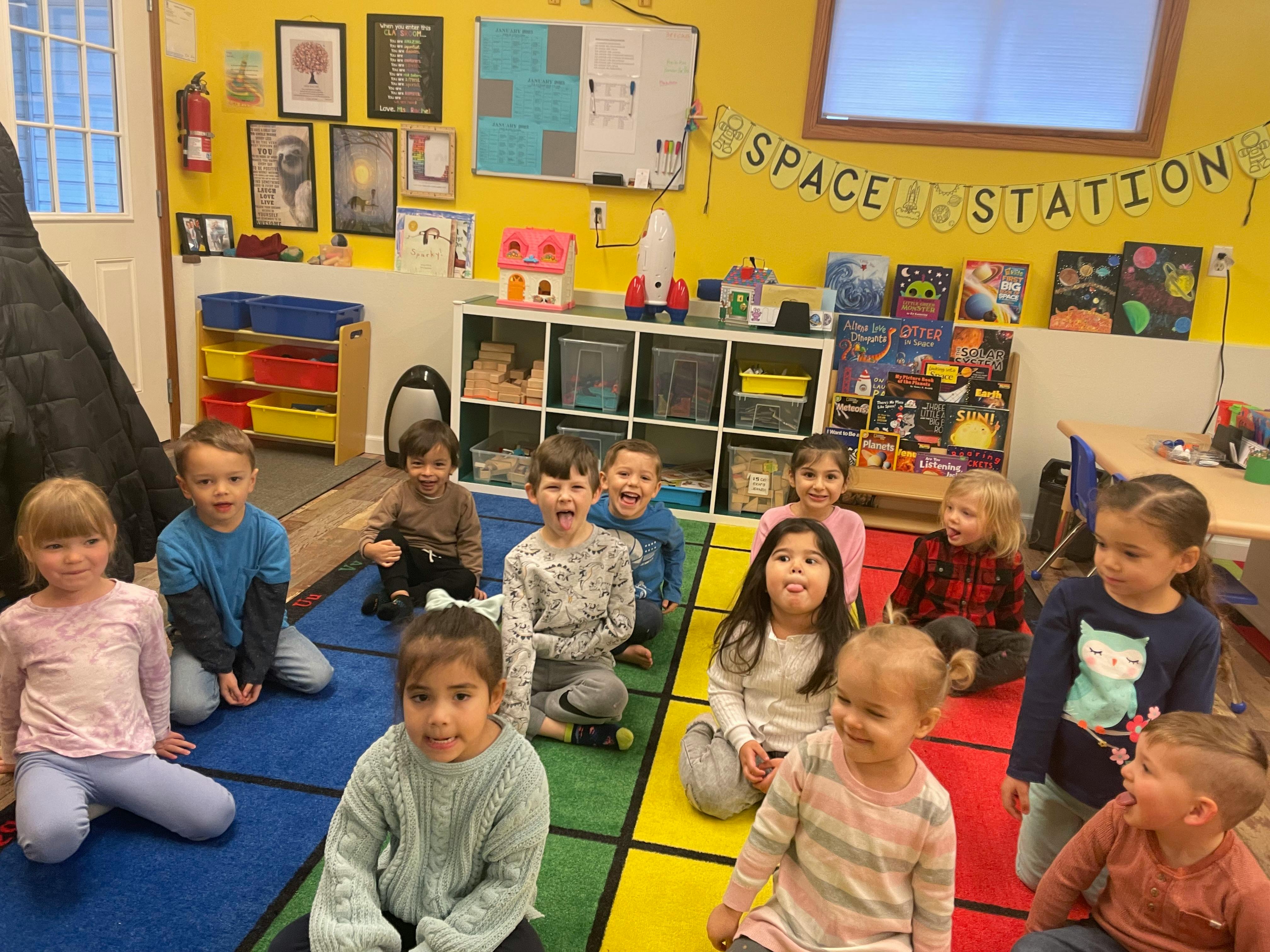 Group of children sitting on a colorful rug in a classroom