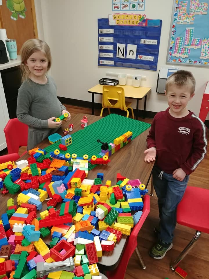 Two children standing at a table with building blocks