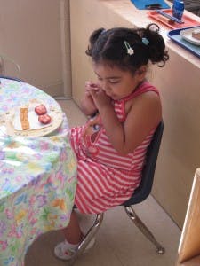 Child sitting at a table with a plate of food
