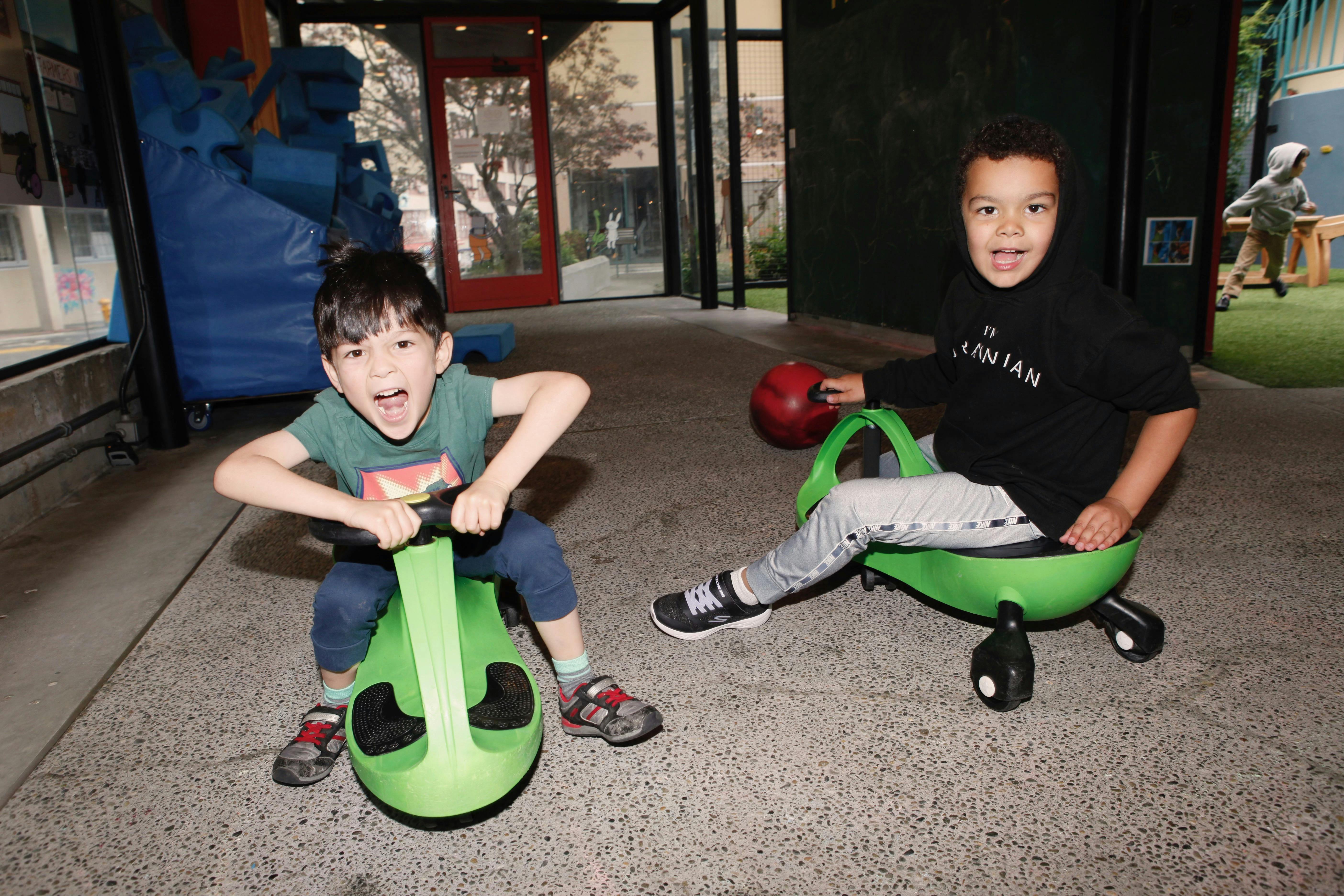 Two children on green ride-on toys