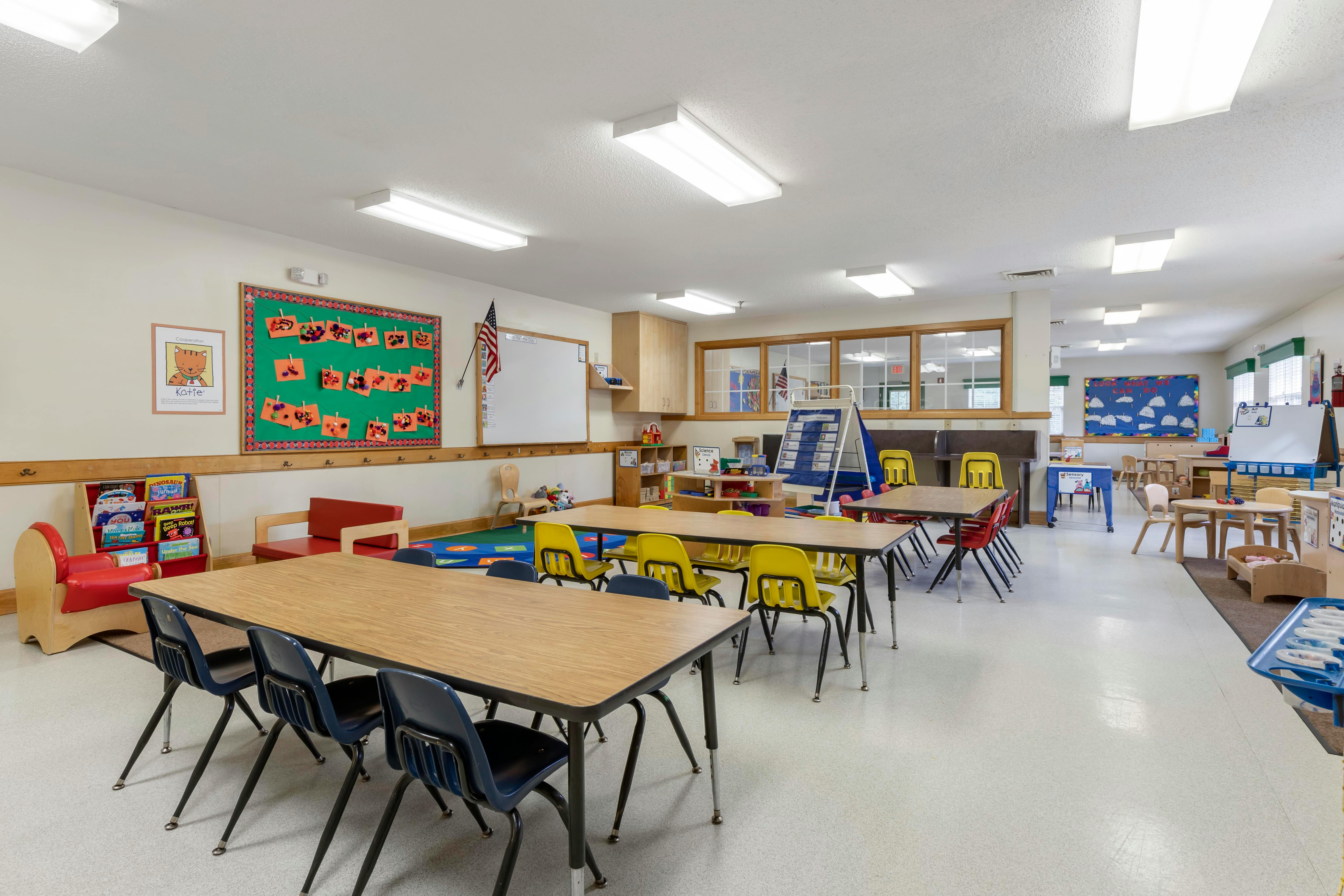An empty elementary school classroom with tables and chairs