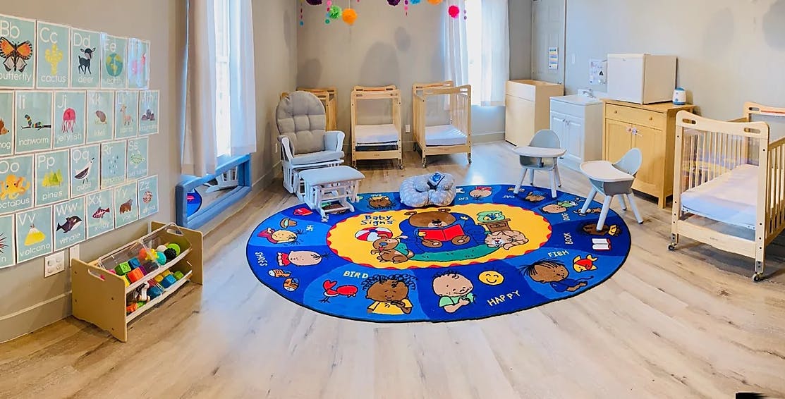 Infant room with cribs, play rug, and storage
