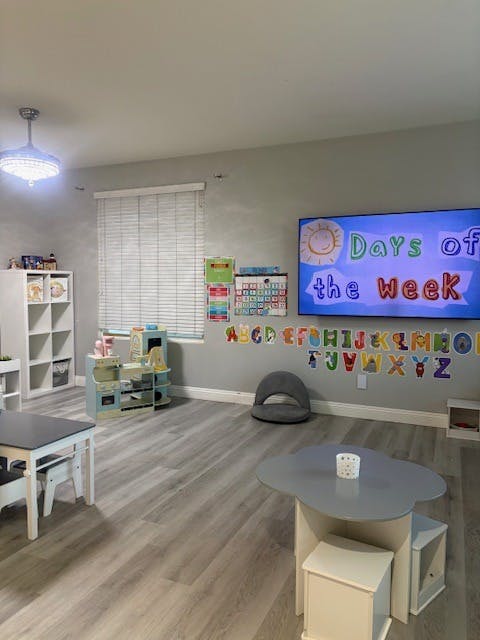 Children's play area with toy kitchen, tables, alphabet wall decals, and TV