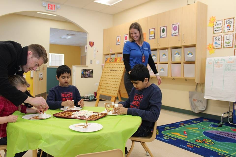 Adults and children eating at a table in a classroom
