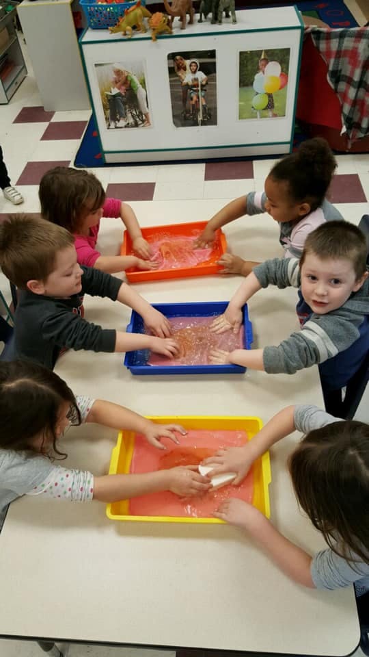 Children playing with sensory bins in a classroom