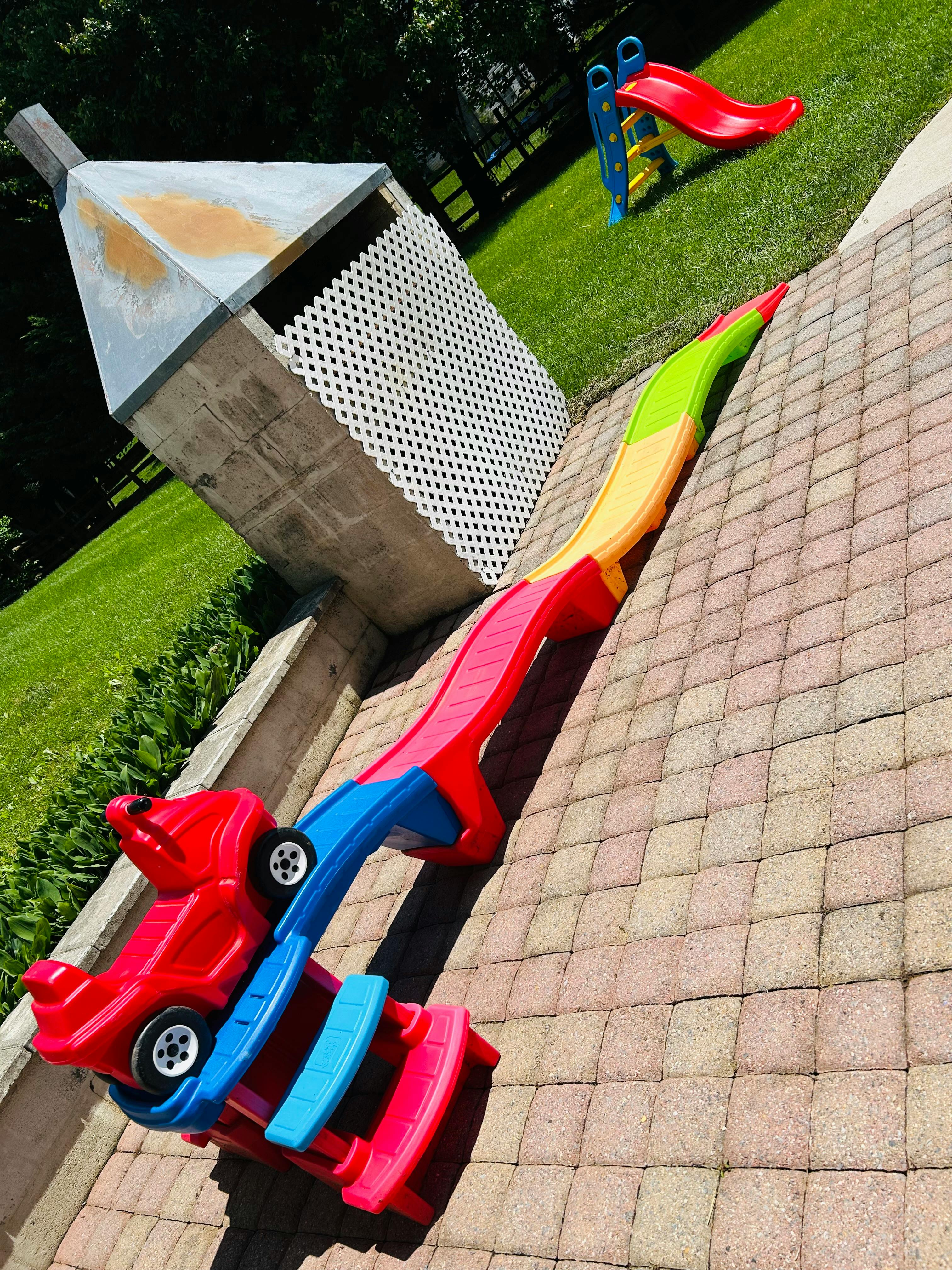 Toy car on a colorful slide next to a paved area