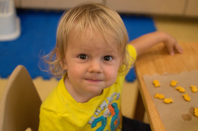 Child in yellow shirt at a table with snacks