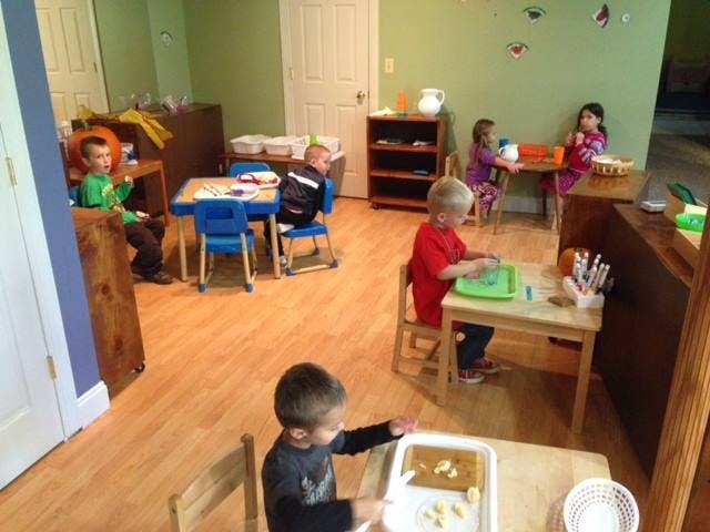 Children in a classroom engaged in various activities at tables