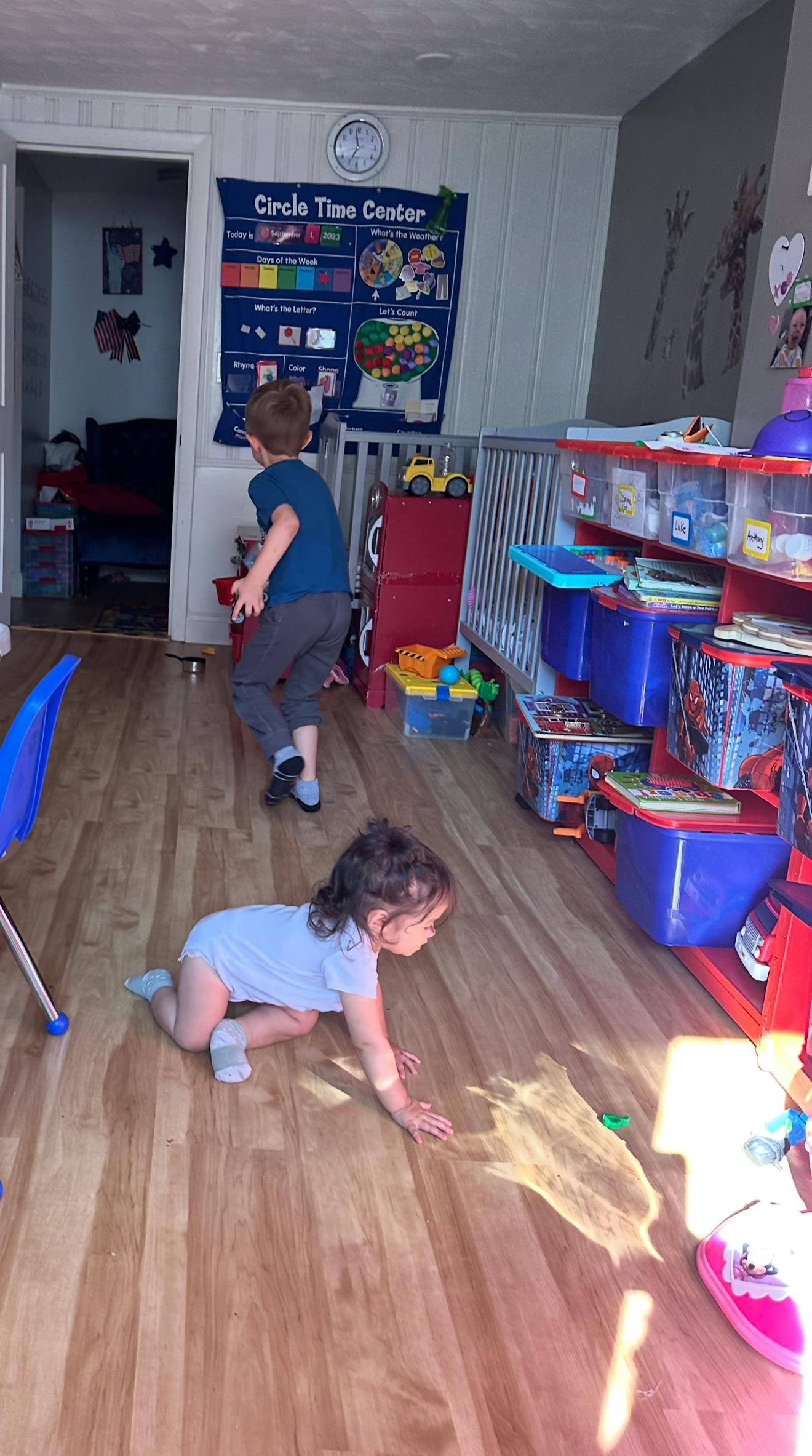 Child crawling on floor with another child standing in background