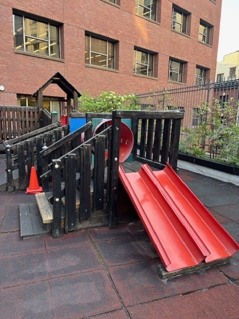 Playground structure with red slides and wooden railings