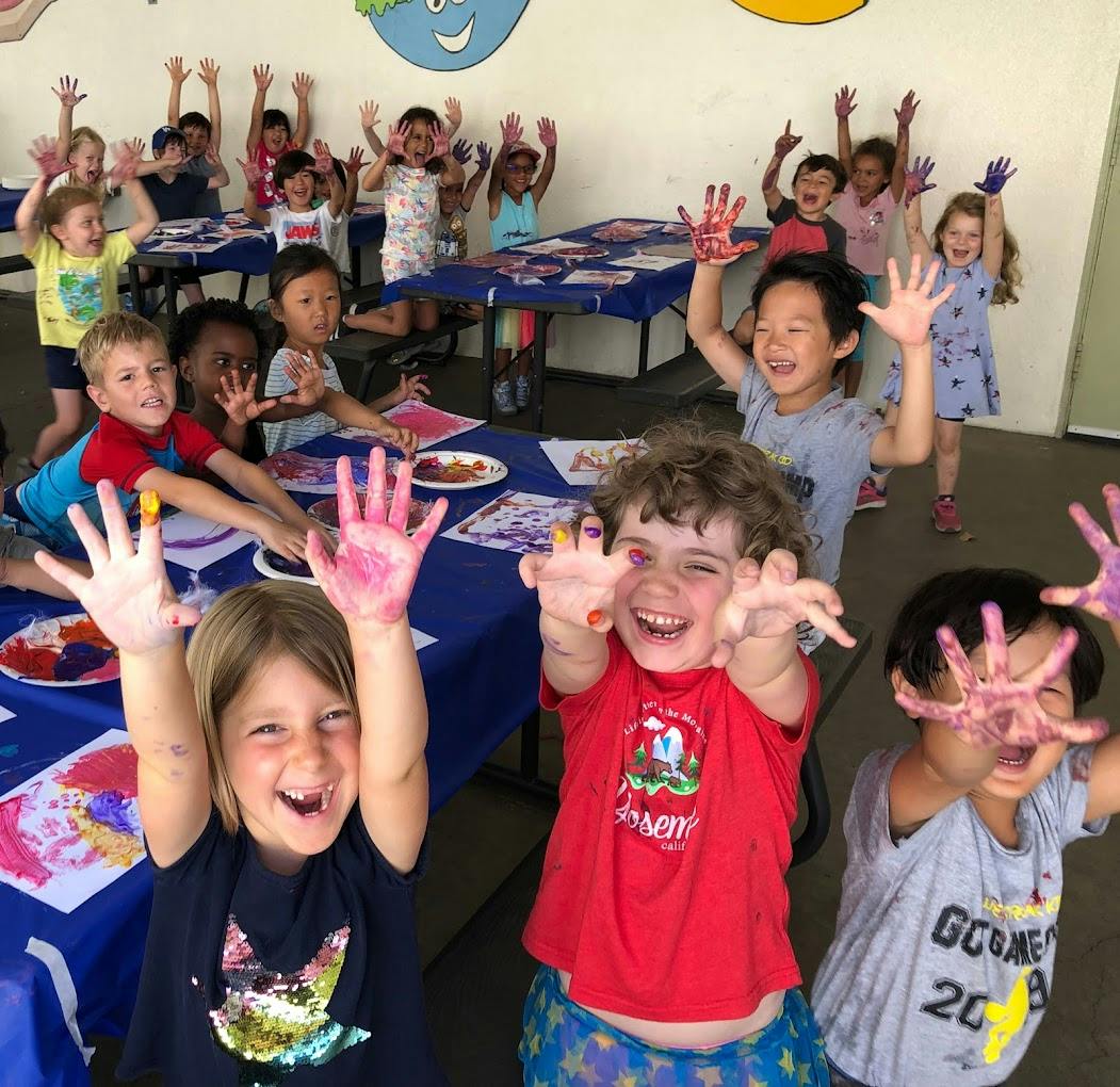 Group of children showing their paint-covered hands during an art activity
