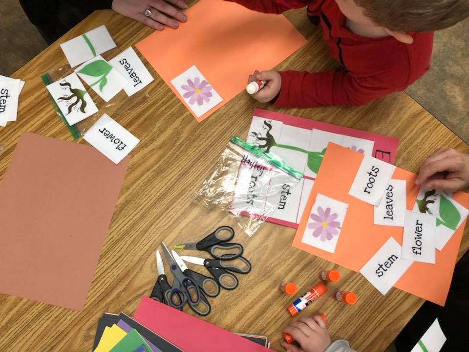 People doing a craft activity with paper cutouts and glue